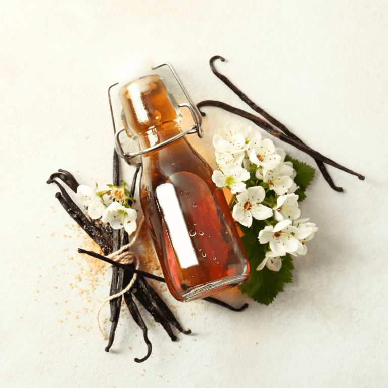 A glass bottle of vanilla surrounded by vanilla pods.