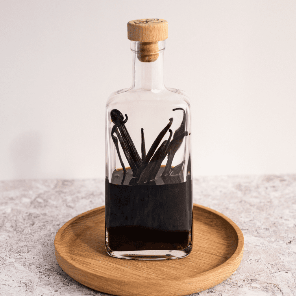 Vanilla pods in a jar with alcohol that has turned dark from soaking to extract the complex flavor.