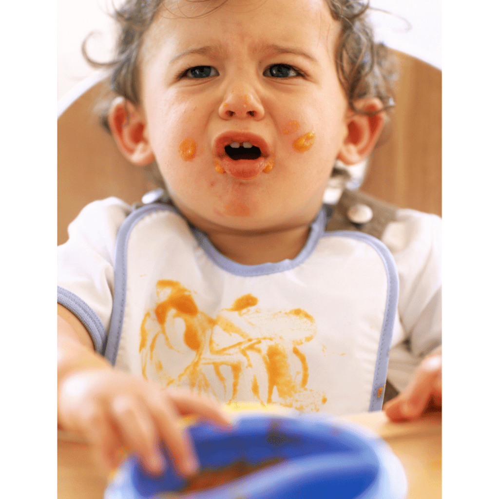 Baby experiencing excessive gagging on solid food and is visibly upset.