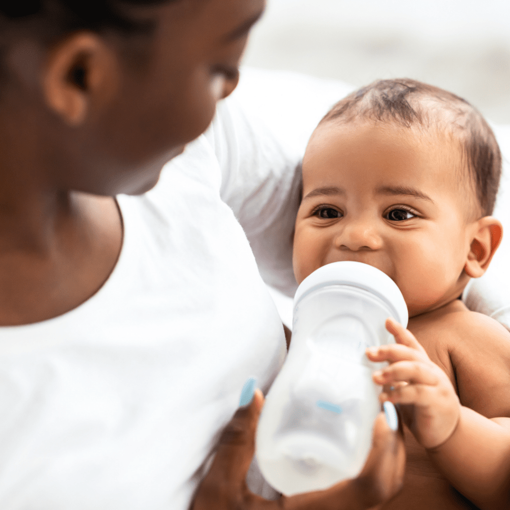 A mother holding their baby as the baby drinks formula from a bottle.