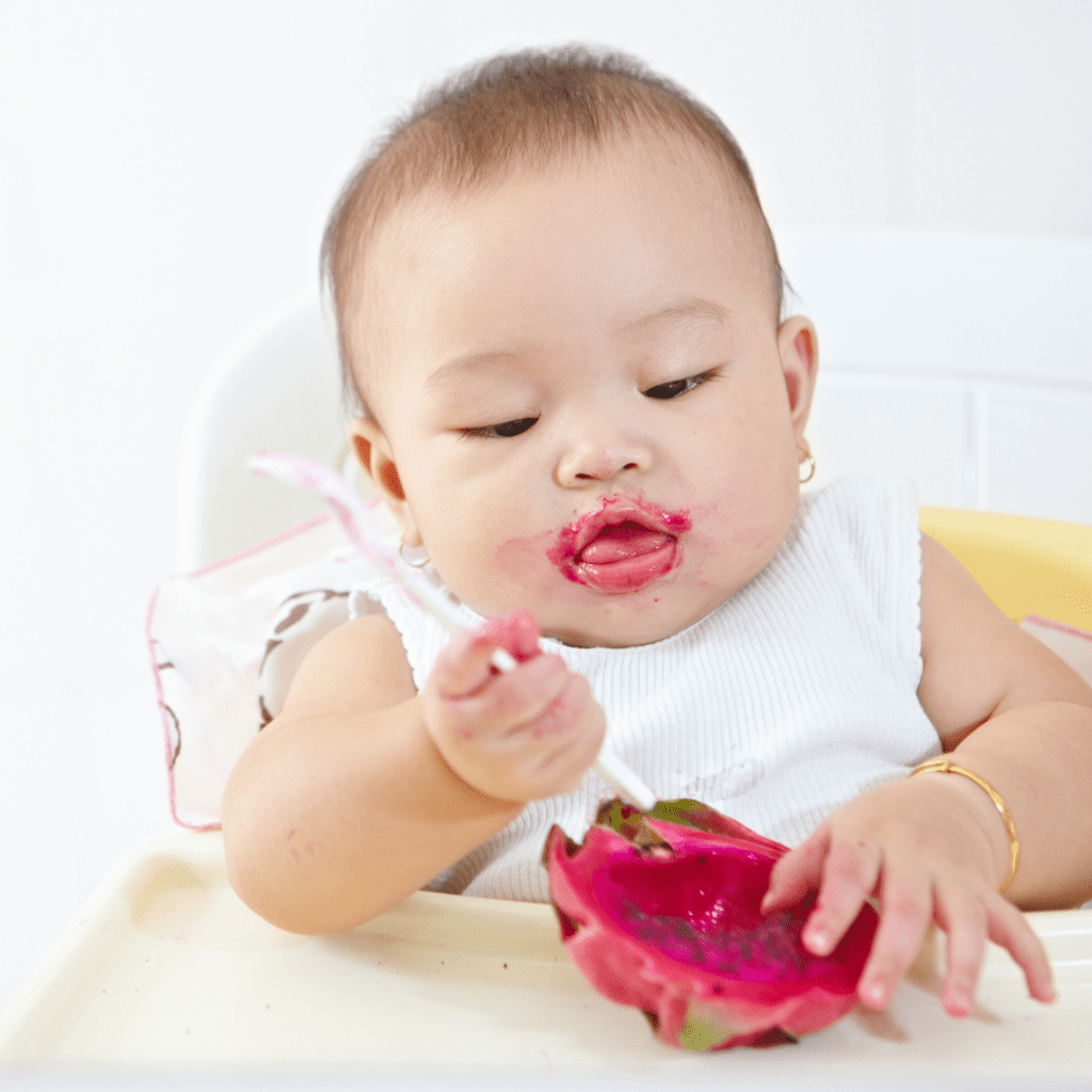 Baby self-feeding on fruit.