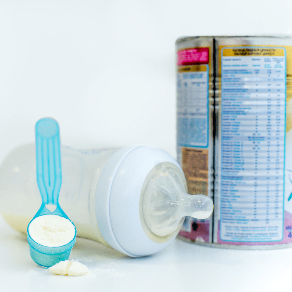 Infant formulas sold in the US follow specific nutrition regulations; nutrition facts table can be seen with a baby bottle and formula scoop.