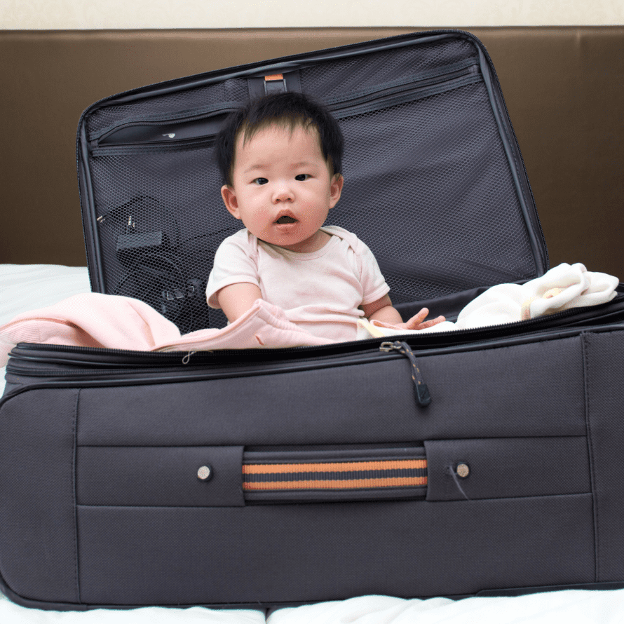 Baby sitting in a suitcase while it gets packed.
