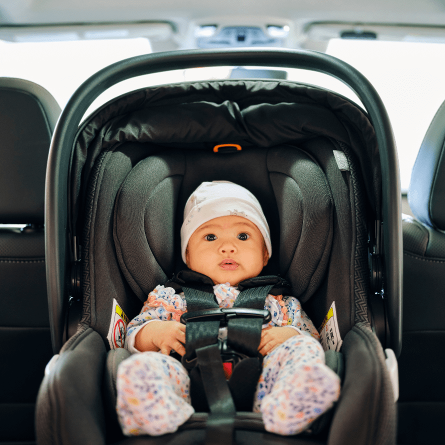 Baby sitting in an infant car seat inside a car.