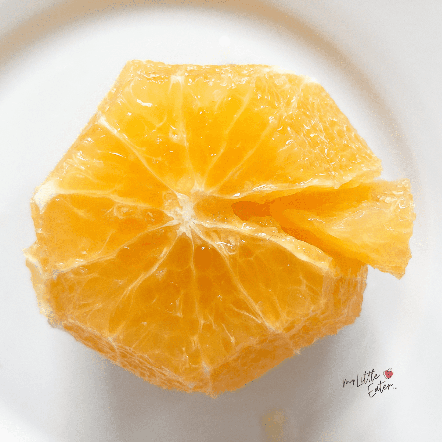 A peeled orange with one wedge sliced out of it.