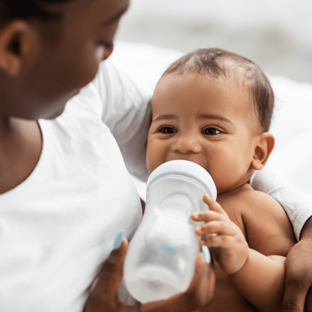 A baby drinking warm breast milk from a bottle.