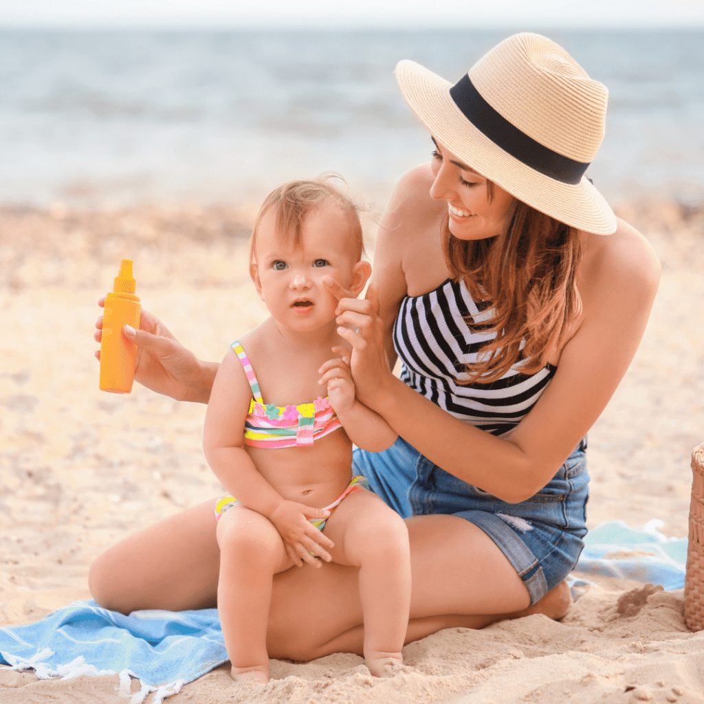 Mom and daughter at the beach; mom applying sunscreen to her daughter's face. 