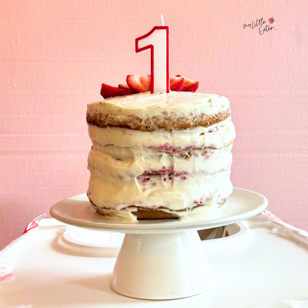 A layer cake on a cake stand with fresh berries ready to eat.