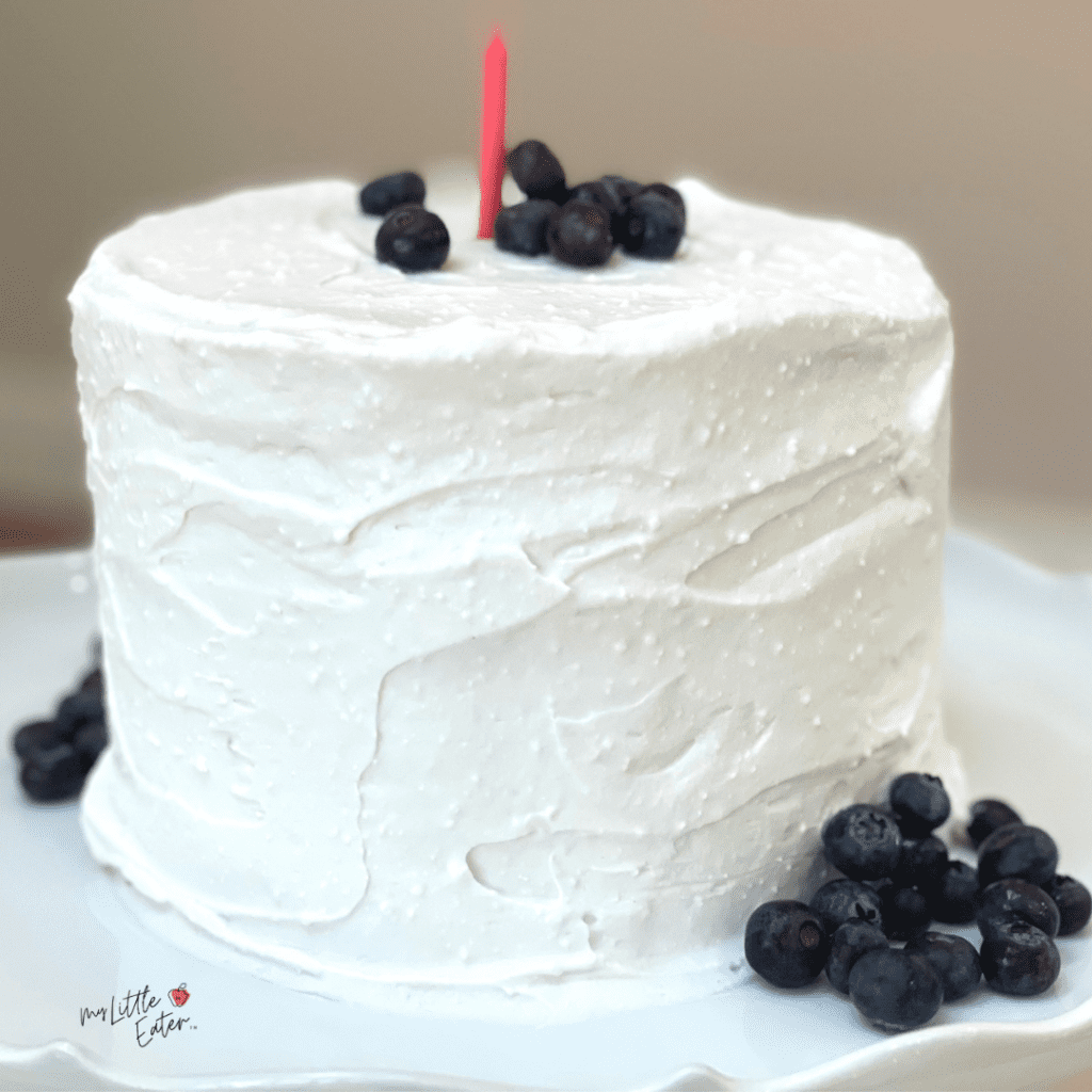 Easy smash cake recipe with coconut whipped cream frosting and topped with blueberries.