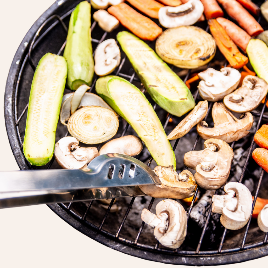 Vegetables like carrots, zucchini, mushrooms, and onion being cooked on the BBQ.