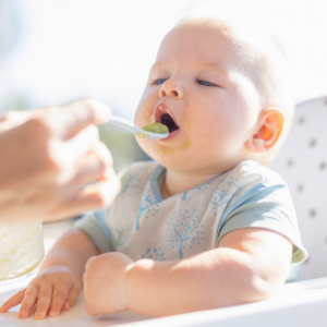 Baby taking a bite of puree while being fed from a spoon.