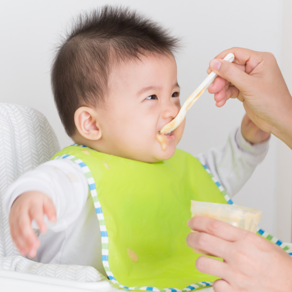 Baby being spoon-fed with the spoon being swiped upwards against baby's palate.