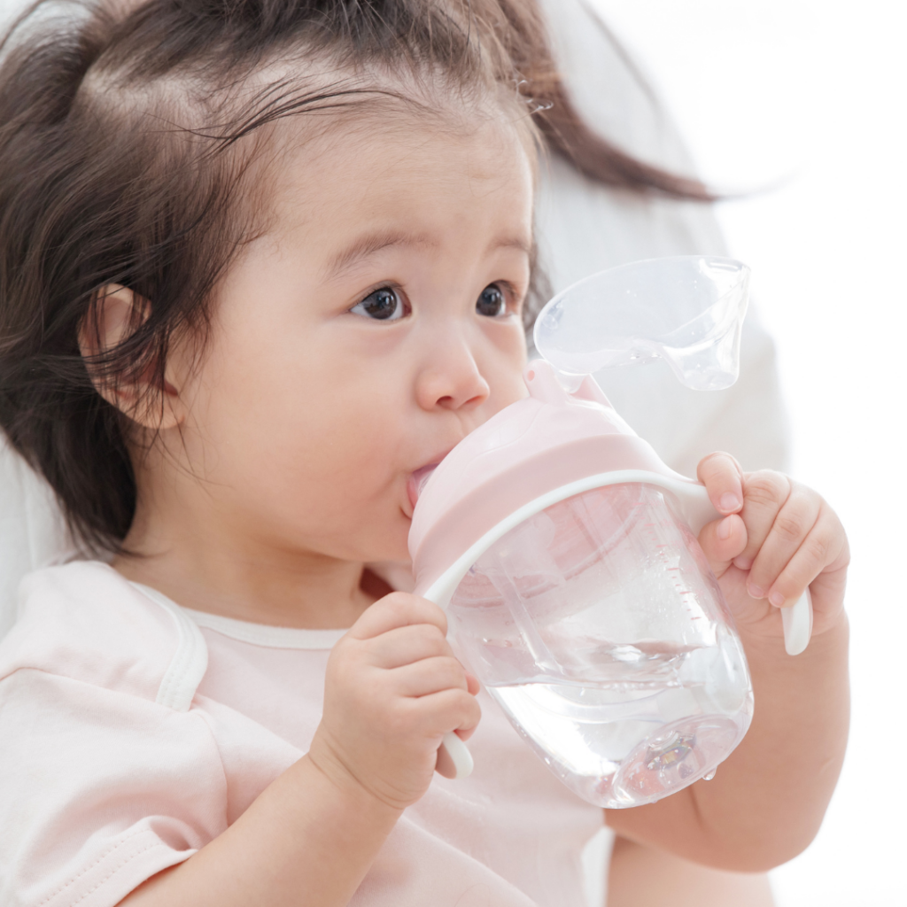 Baby drinking from a straw cup with handles.