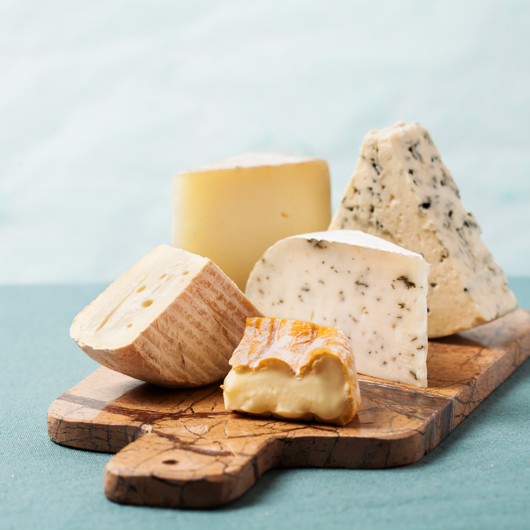 Multiple types of cheese placed on a wooden cutting board.