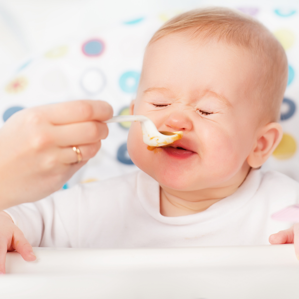 Baby wincing at incoming spoon full of baby purees.