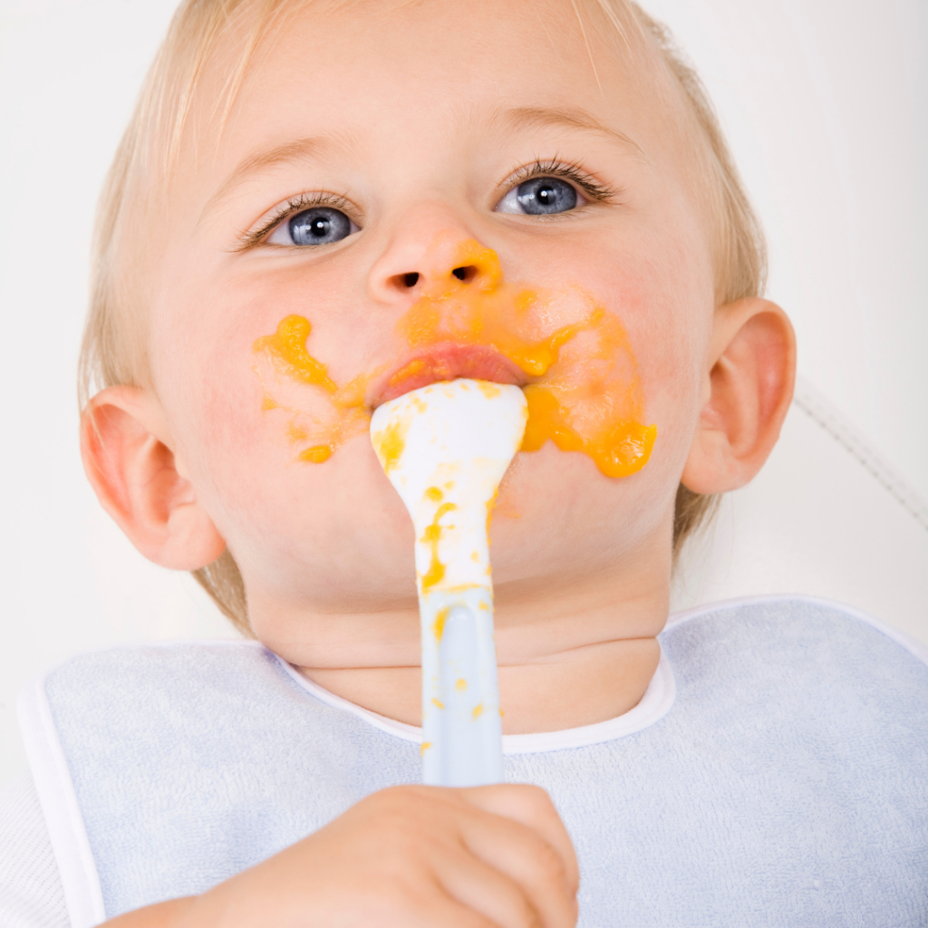 Baby eating sweet potato with a spoon.