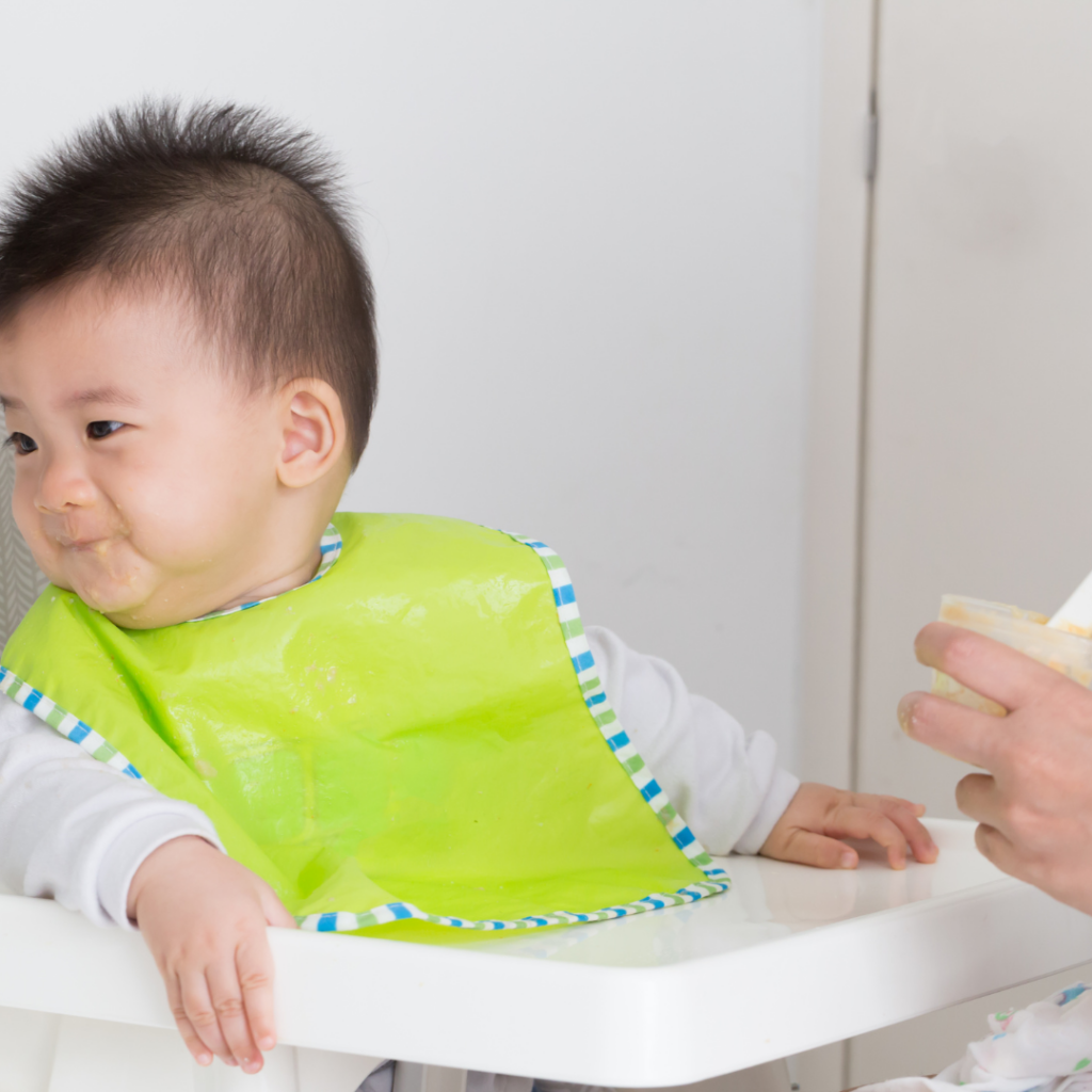 A baby turns their head away, refusing to eat the purees or finger foods being offered.