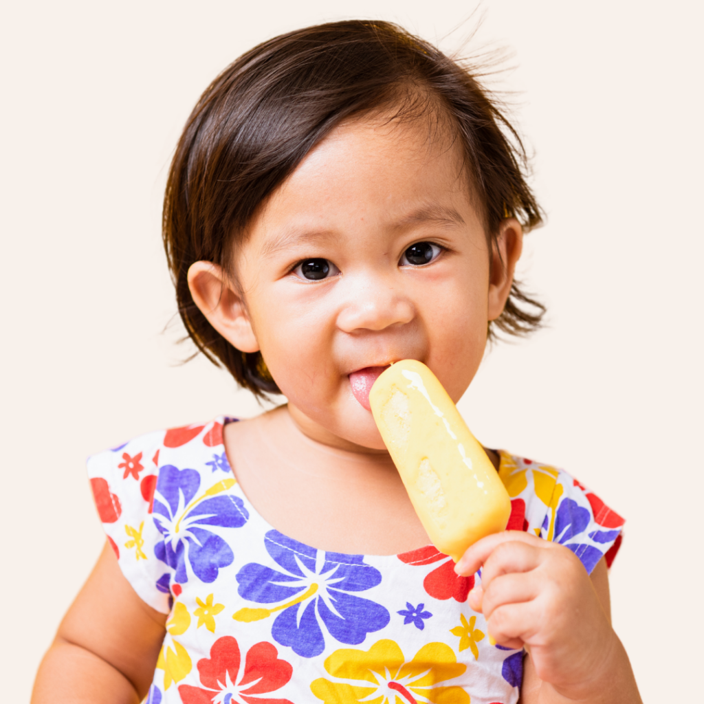 Toddler licking a yellow popsicle.