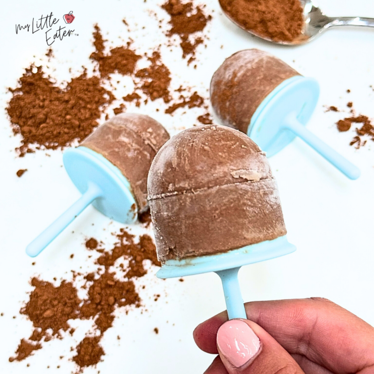 Homemade fudgsicles with cocoa powder in the background.