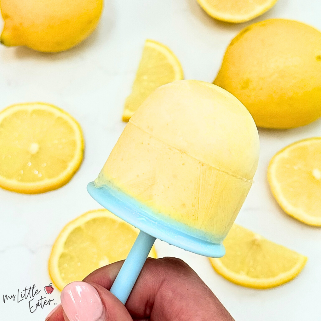 Cold popsicle made with lemons (shown in the background) for a lemonade flavor.