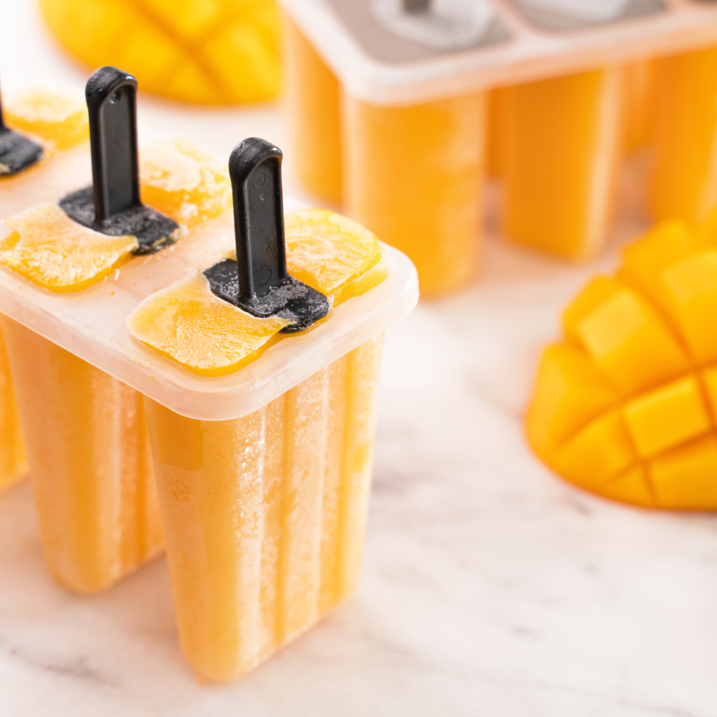 Plastic popsicle molds with mango popsicles inside.