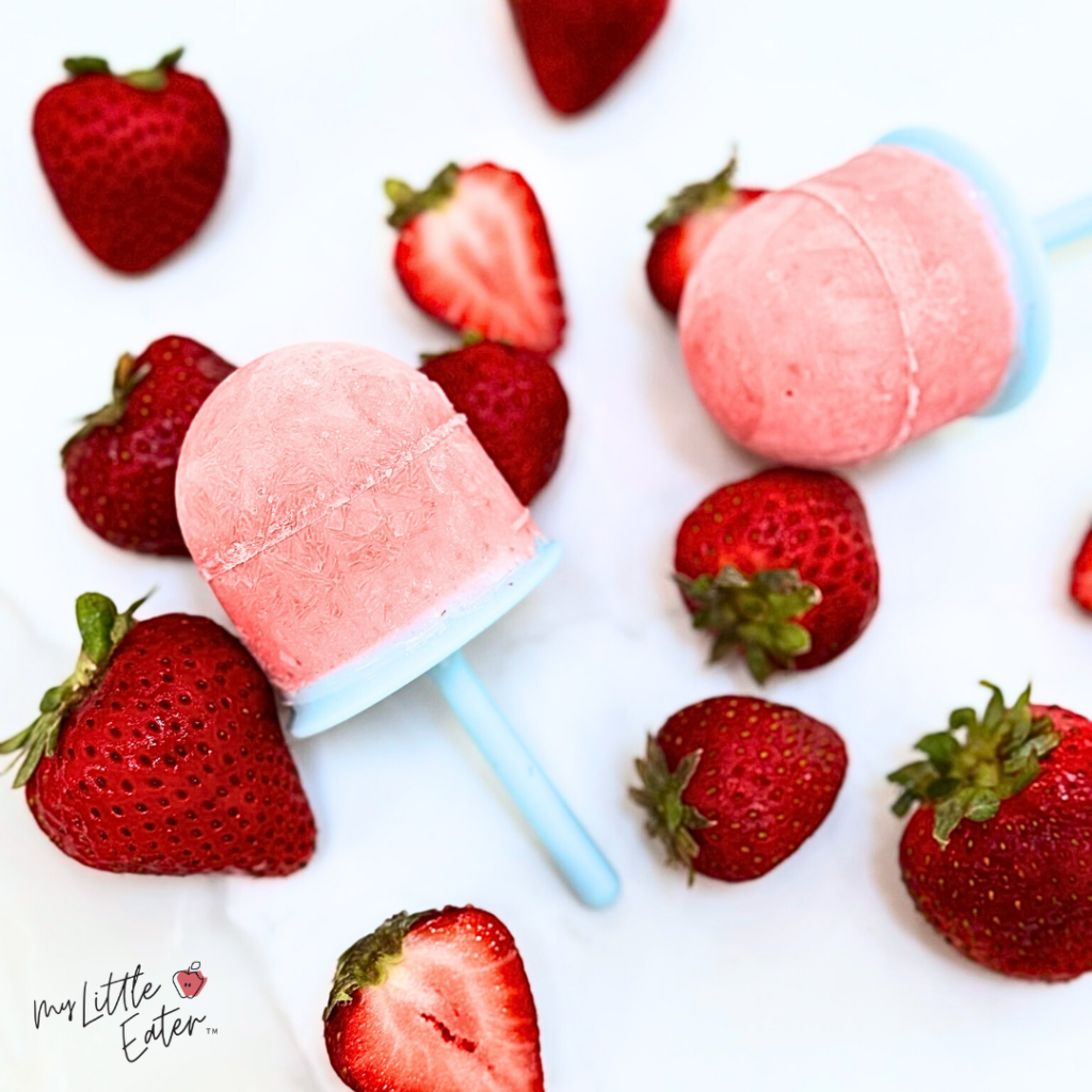 Two pink popsicles with strawberries.