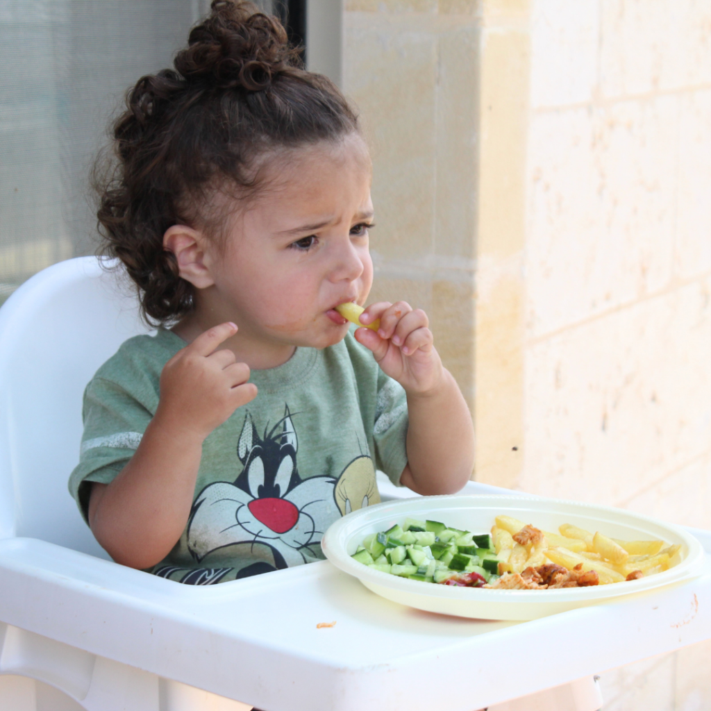 Baby eats while sitting calmly in their high chair.