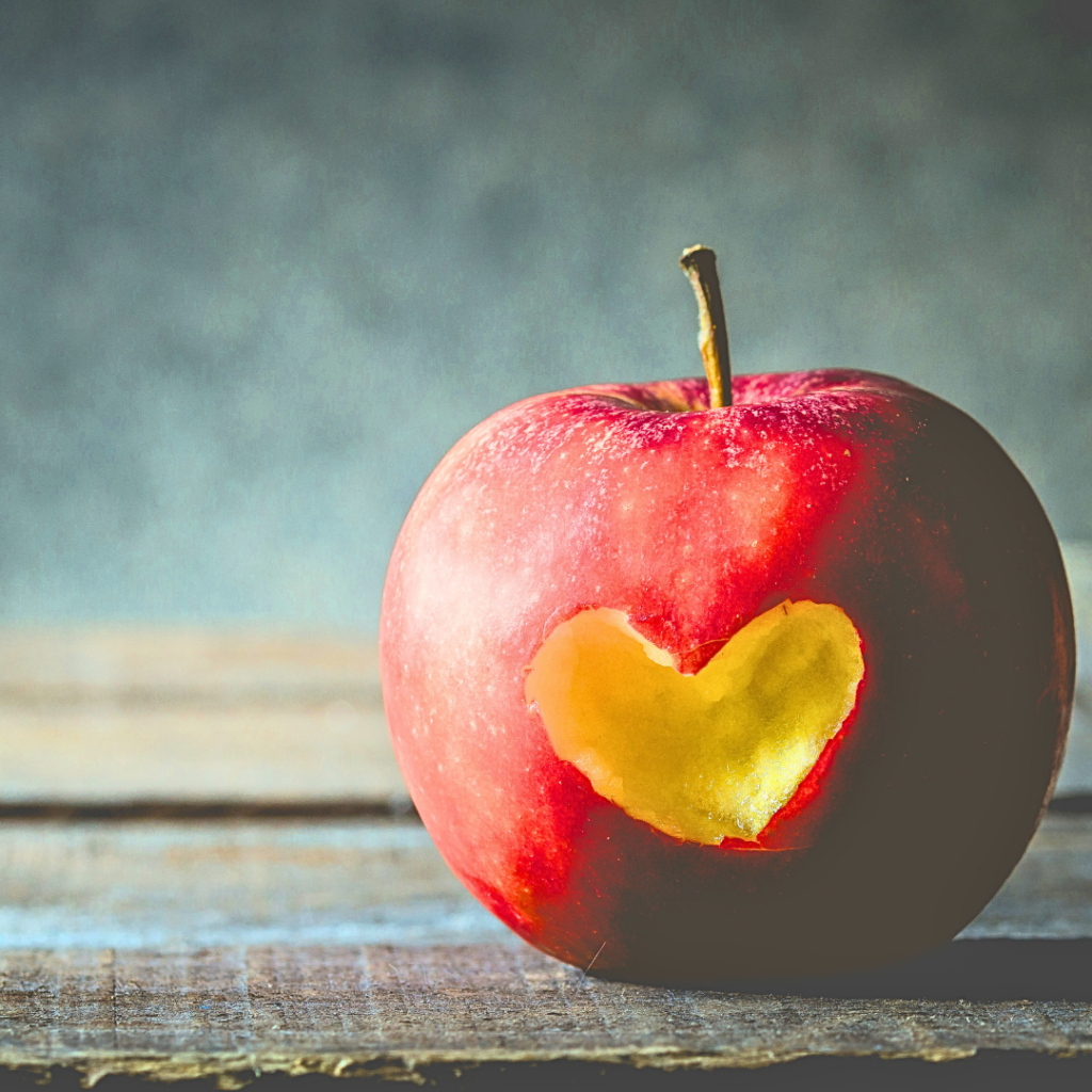 A red apple with a bite taken out of it in the shape of a heart.