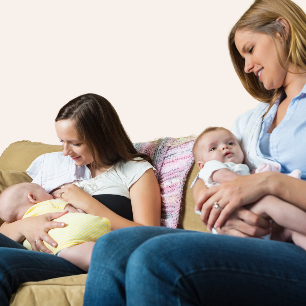 Two moms hold their babies on a couch, one mother breastfeeds.