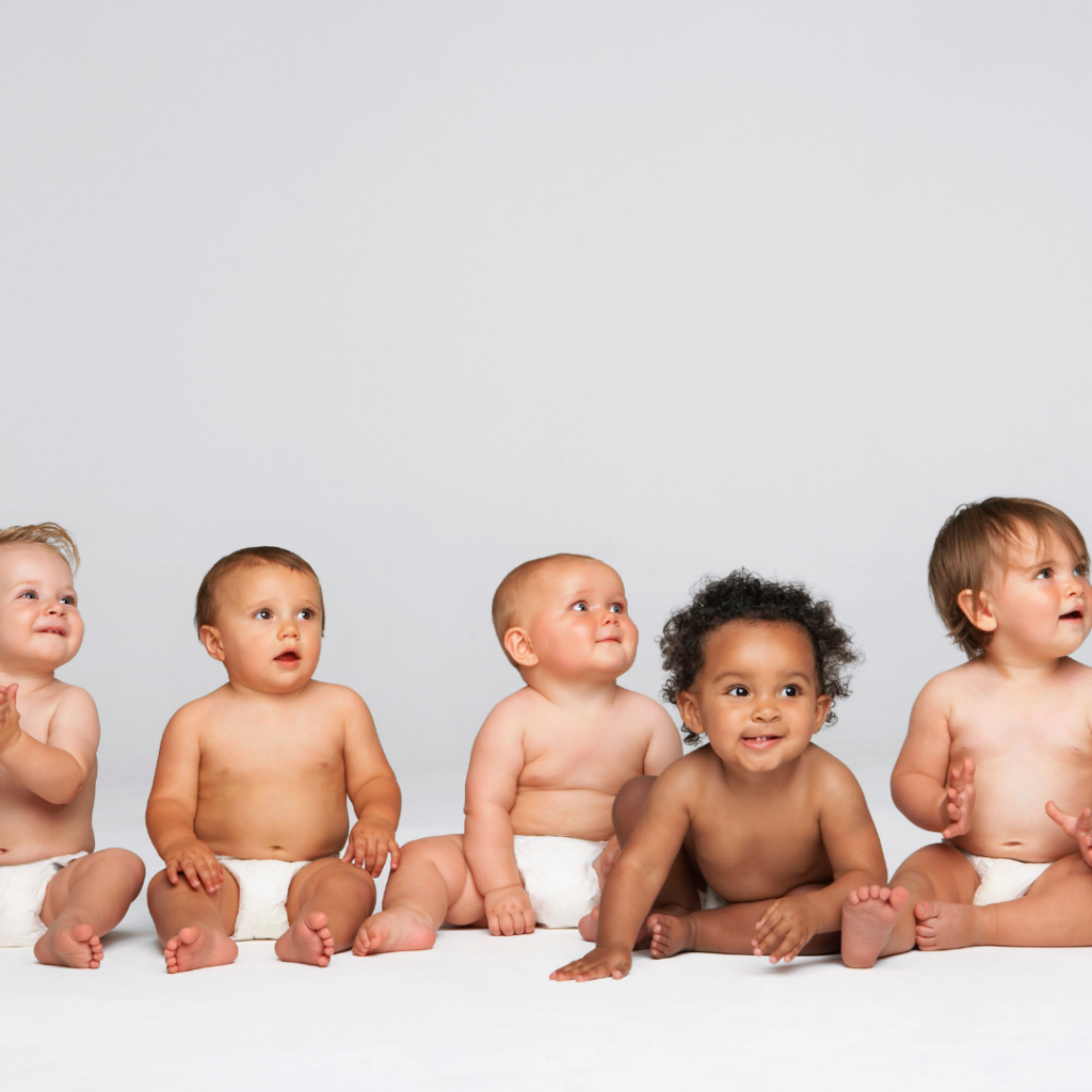 Female babies and male babies of varying sizes and races, but with similar developmental milestones, sit in a row.