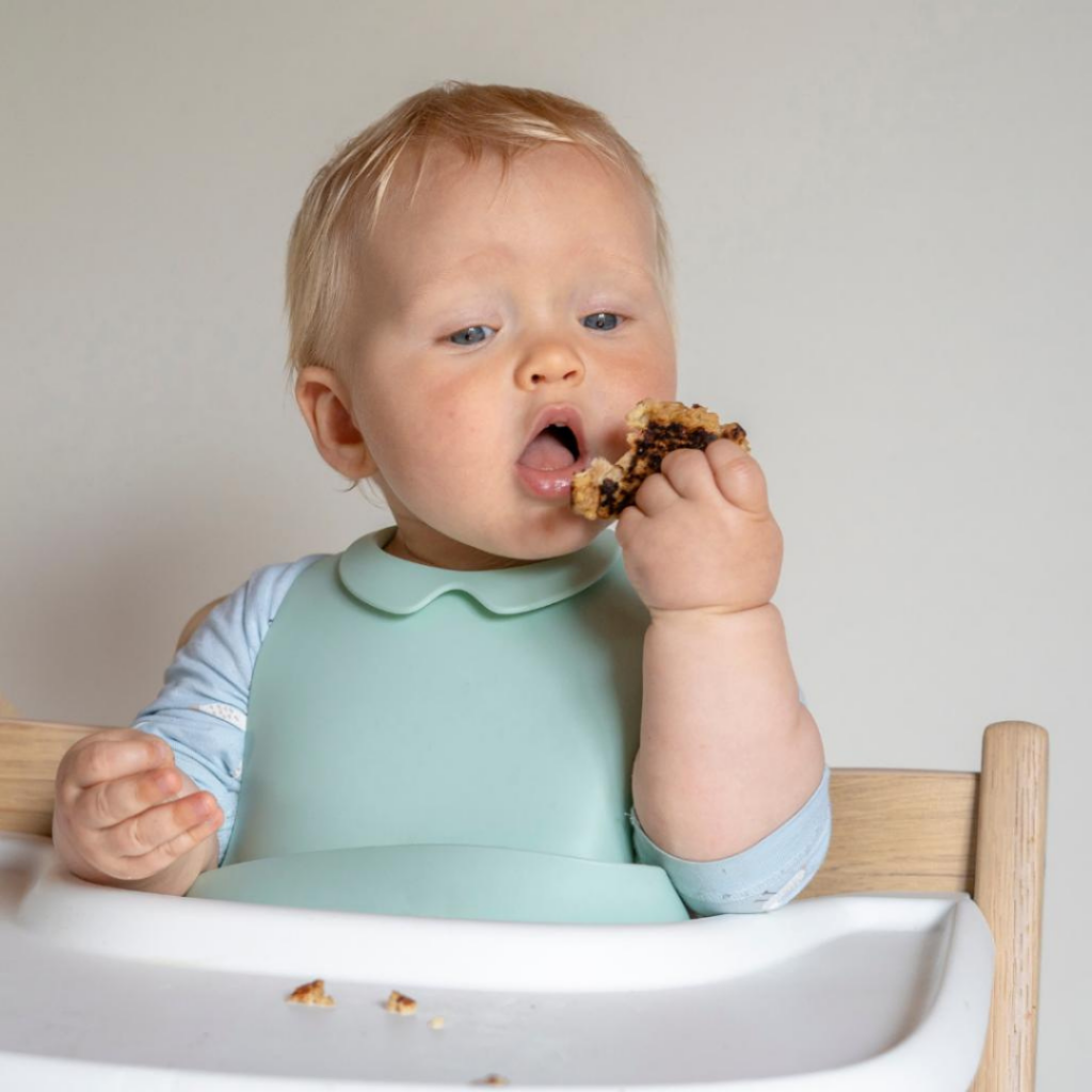 Baby self-feeding in a high chair.