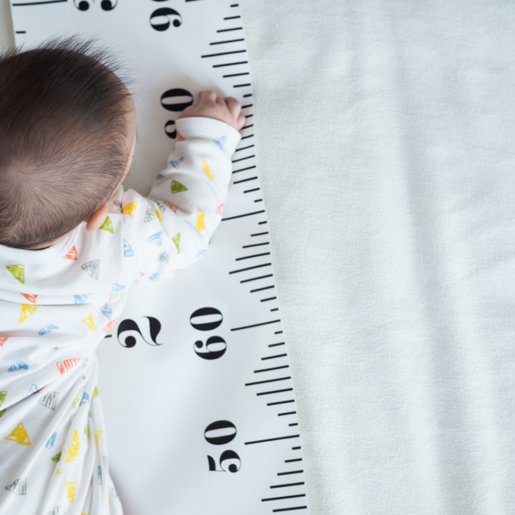 Baby crawls across a large ruler tracking infant growth in length.