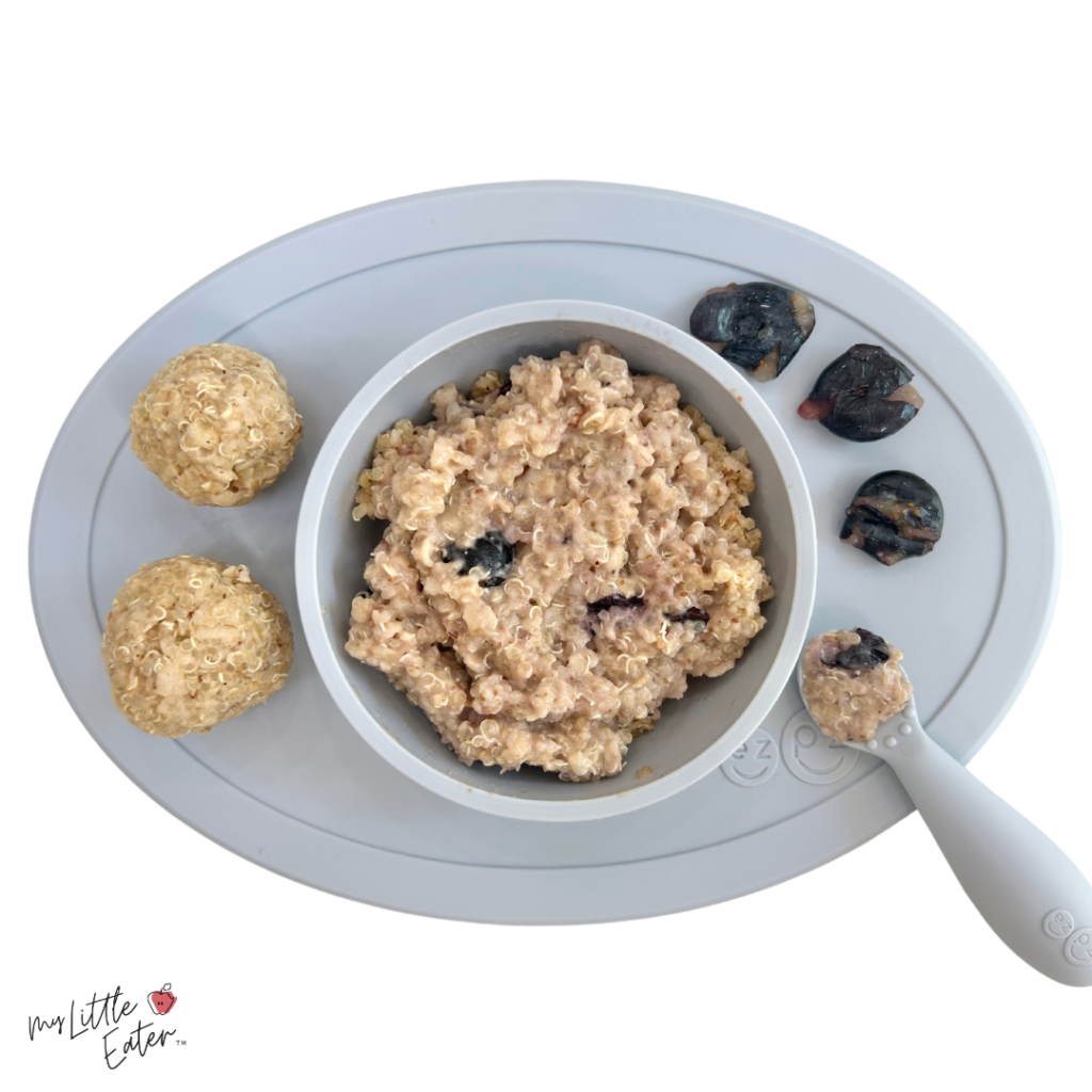 Peanut butter quinoa porridge with flattened blueberries; a mix of puree and finger foods for baby led weaning.