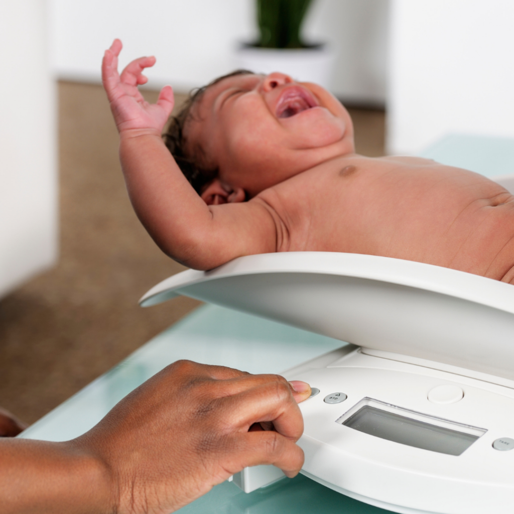 Newborn baby being weighed to compare to average baby weight or check for low birth weight.