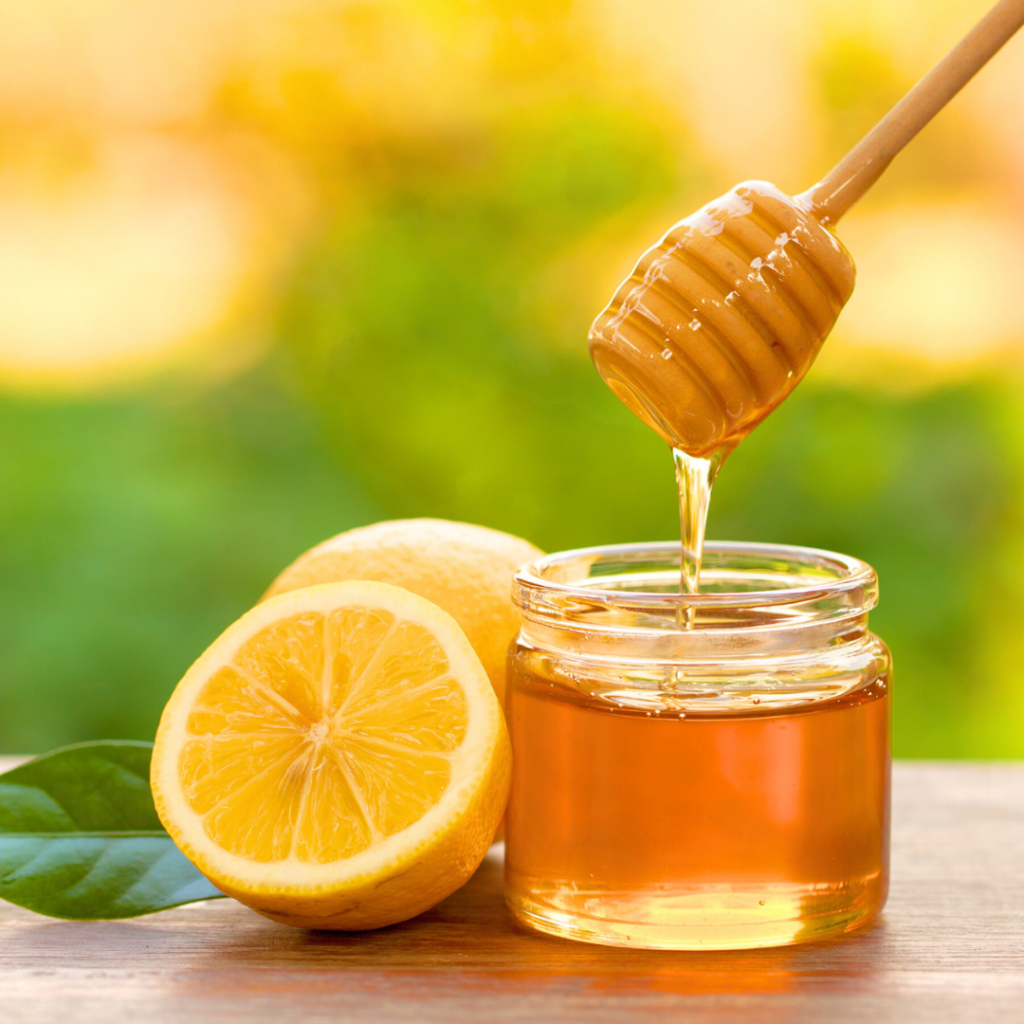 Jar of honey with freshly cut lemons.