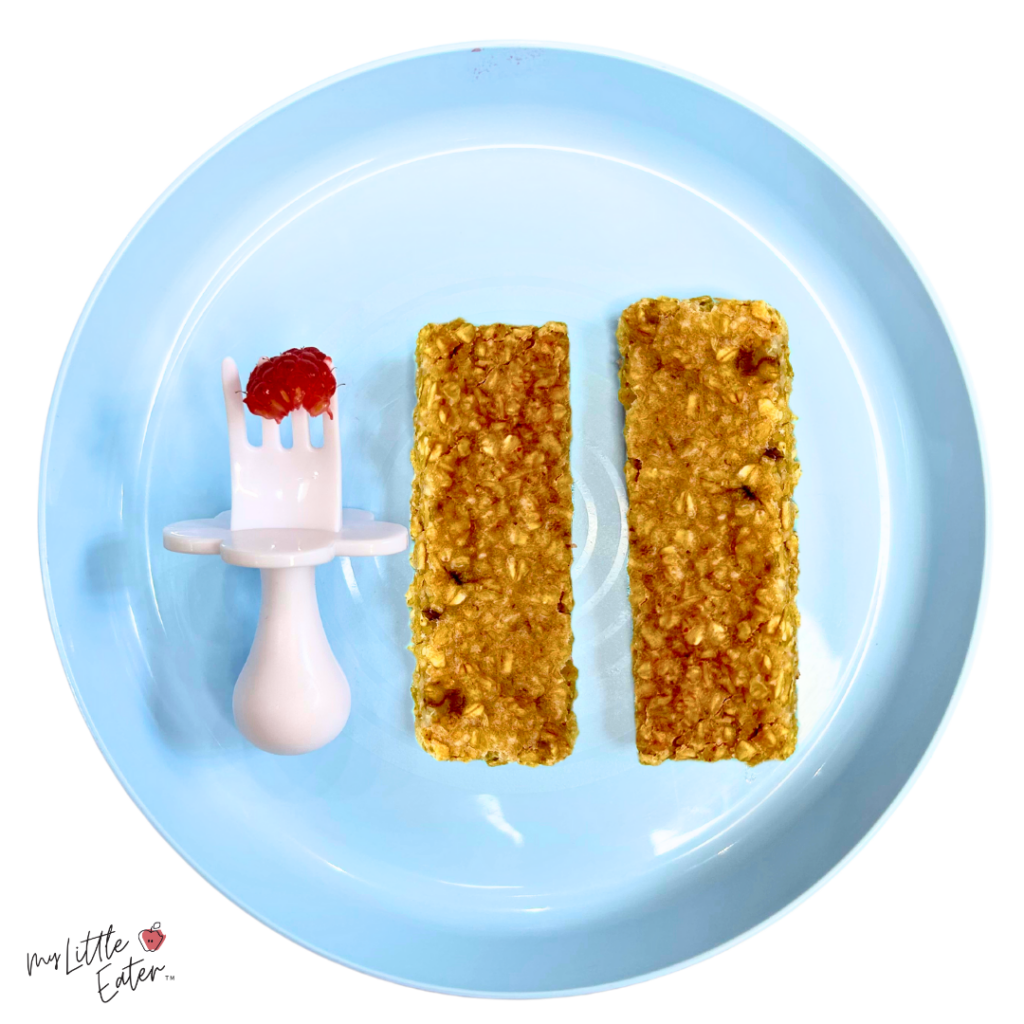 Oatmeal bars with a raspberry on a baby fork beside them.