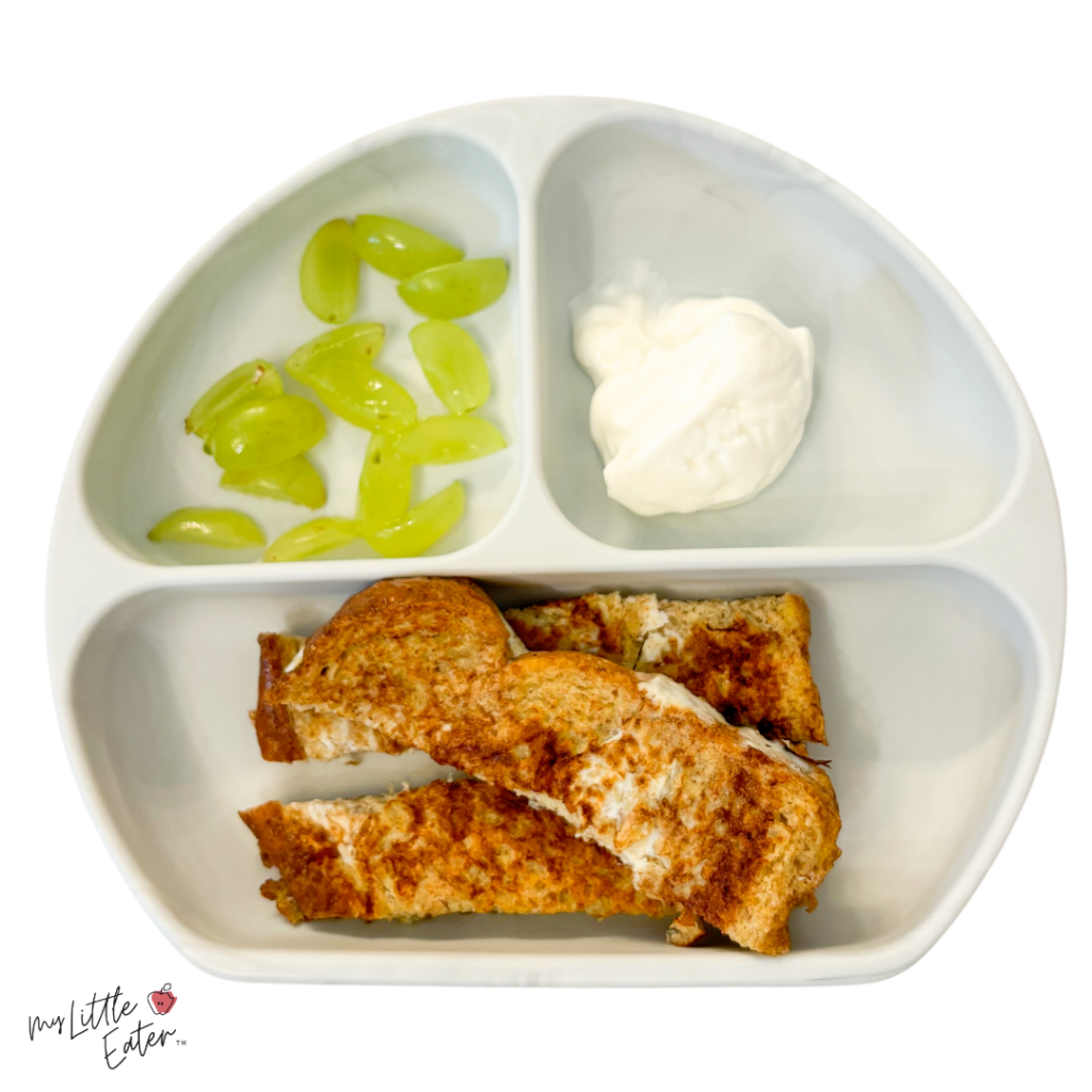 French toast sticks, quartered grapes, and Greek yogurt on a divided baby plate for baby led weaning.