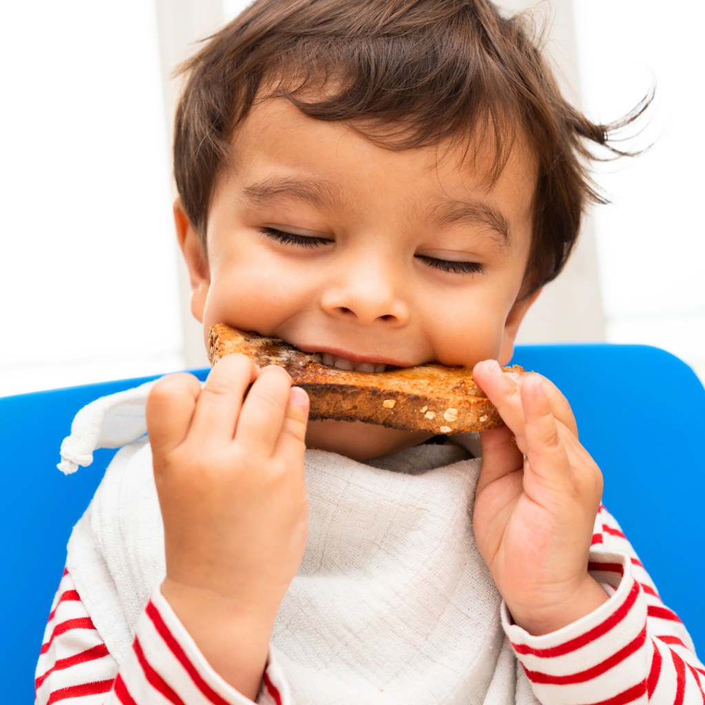 A baby biting into a piece of toast.