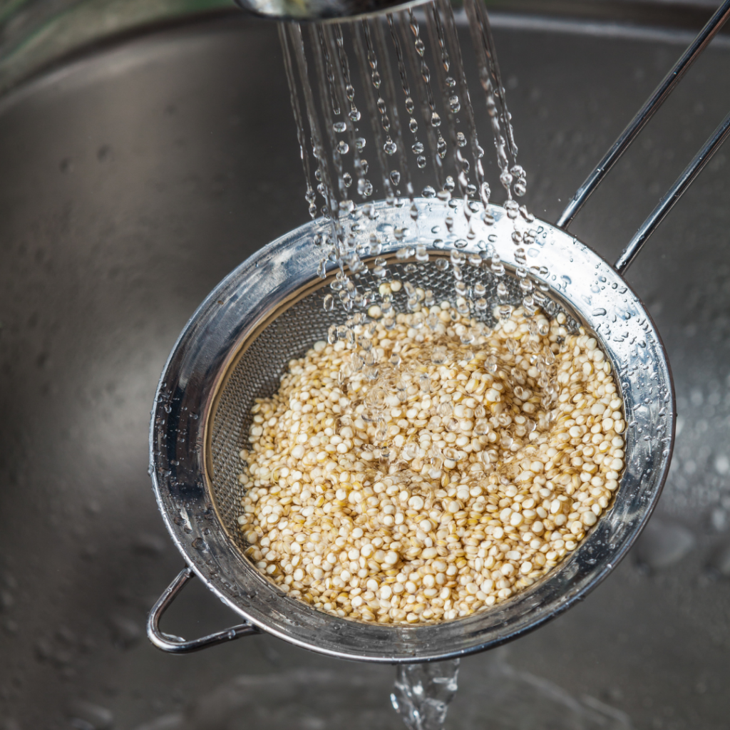 Rinsing quinoa under cold water in a mesh strainer.