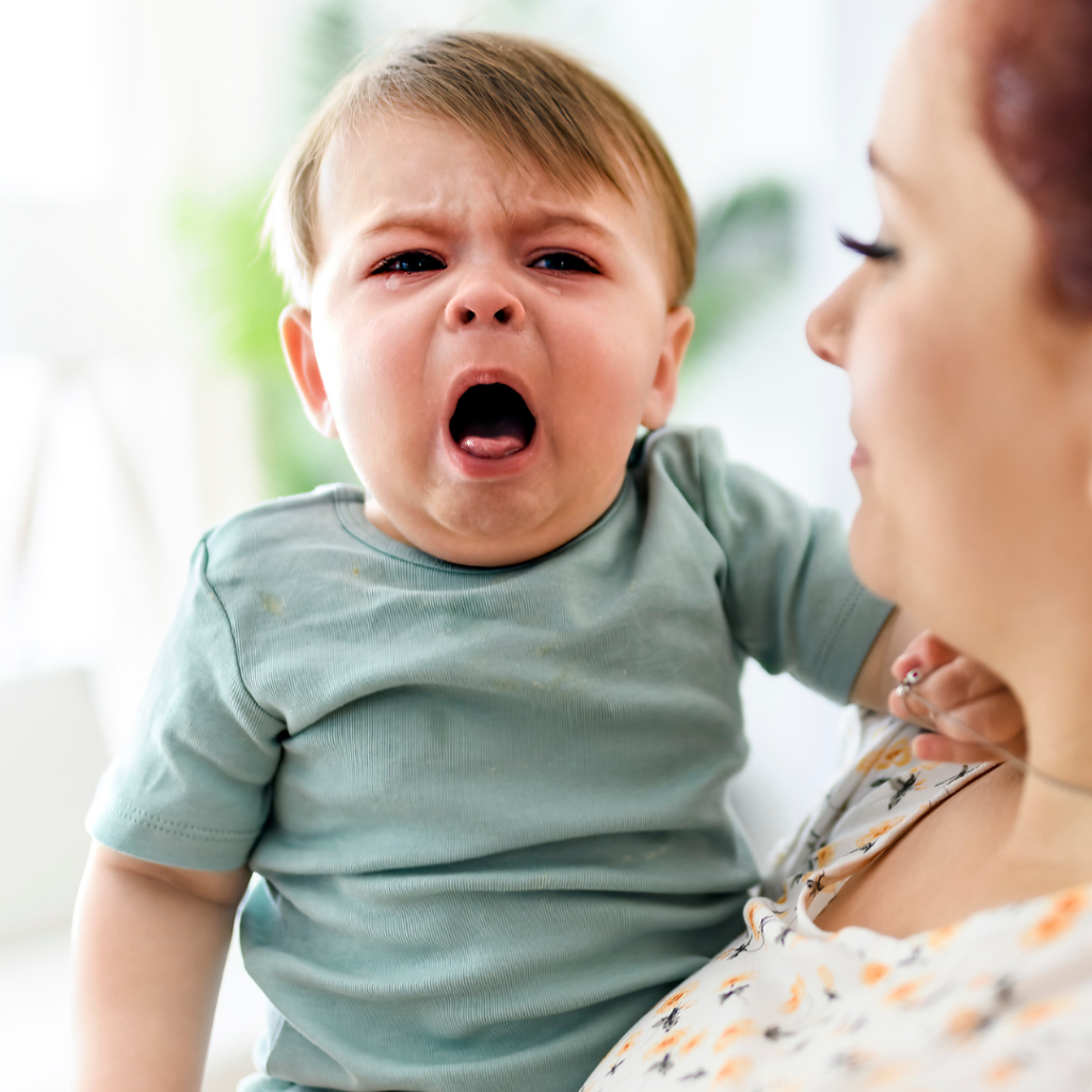 A baby about to vomit which is a common FPIES allergic reaction when you offer your baby shellfish.