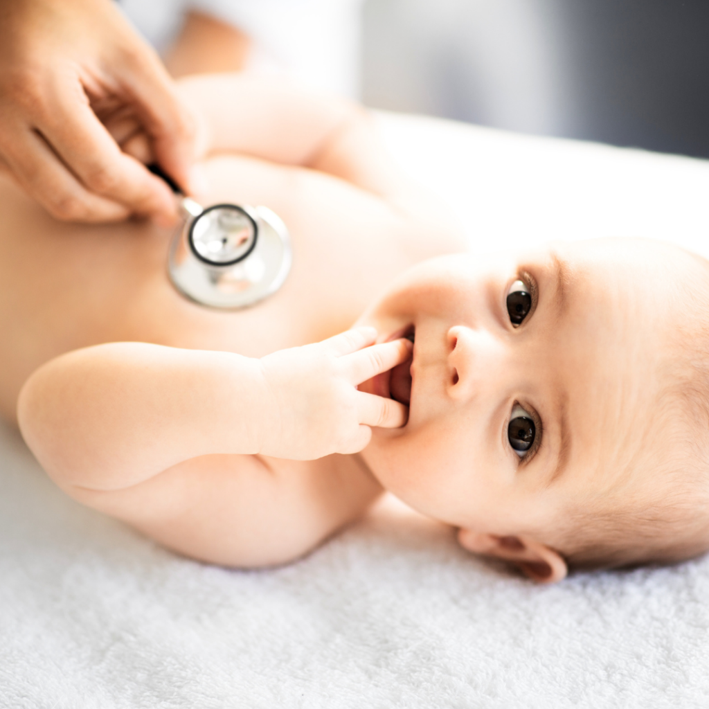 A smiling baby being examined by a doctor.