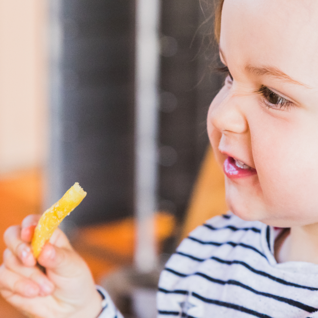 Baby eating a salty food, specifically a french fry.