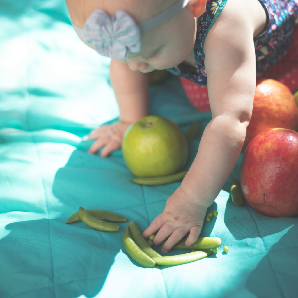 Baby exploring foods on a blanket to experience different food textures.