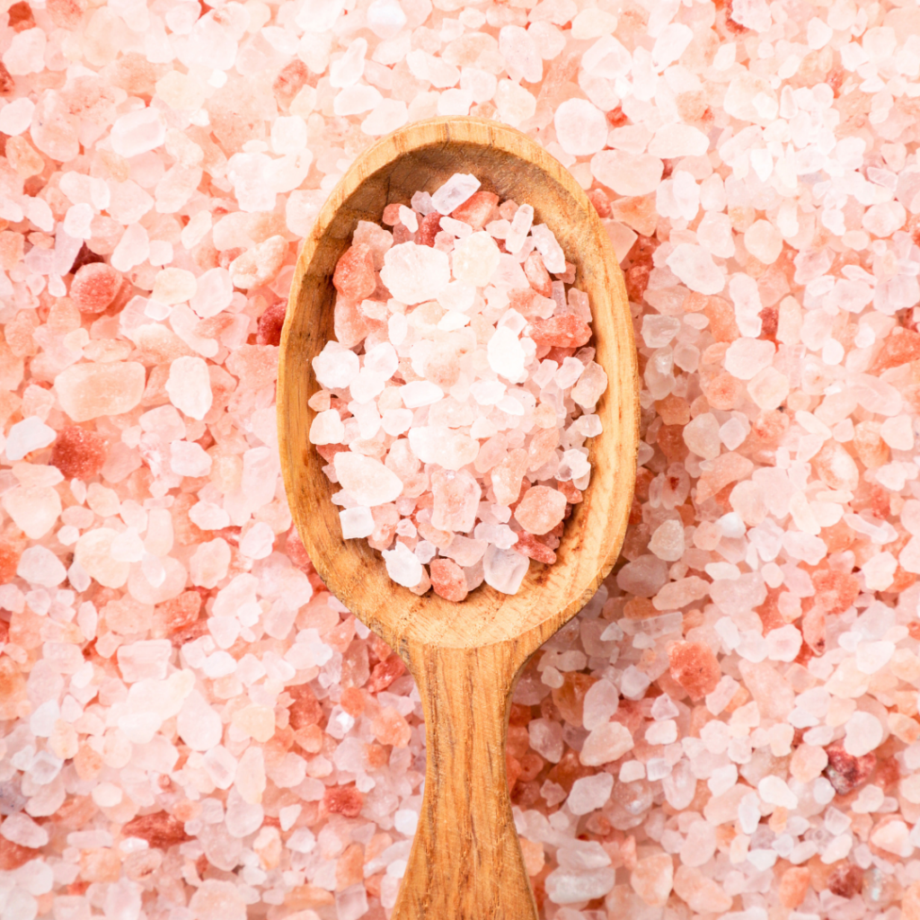 Pink salt with some resting in a wooden spoon.