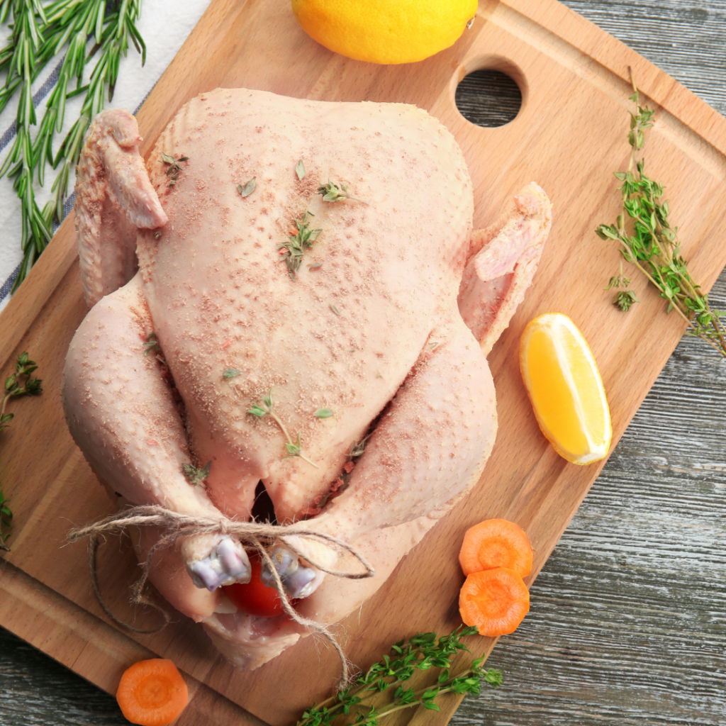 A whole turkey being prepped on a cutting board for cooking.