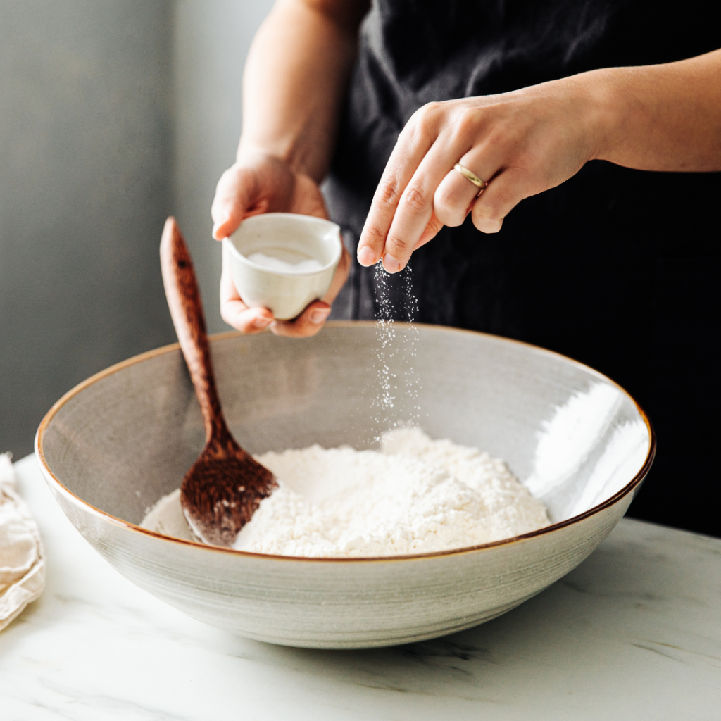 Sprinkling salt into a dish while cooking.