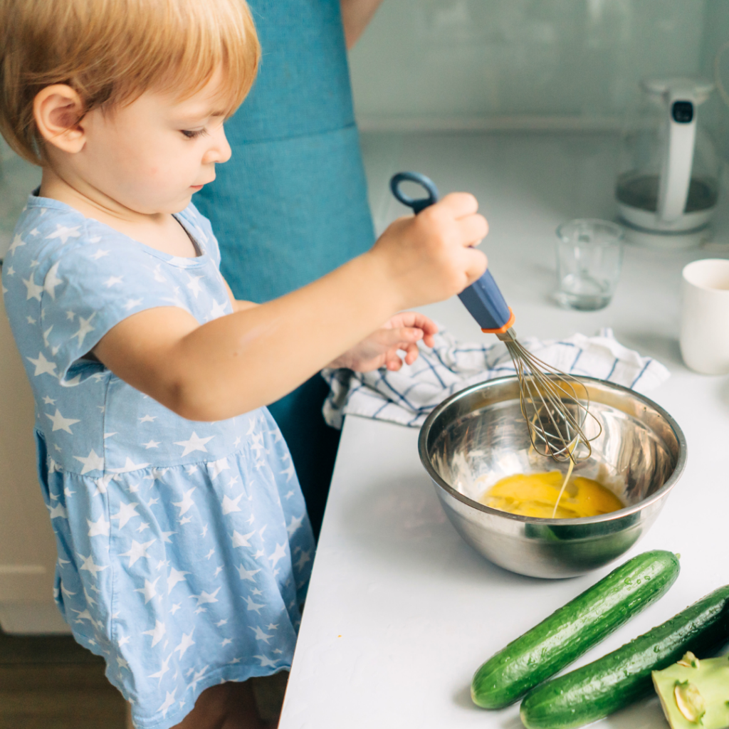 A toddler helping their parent cook homemade meals to avoid too much salt or excess salt in their food.