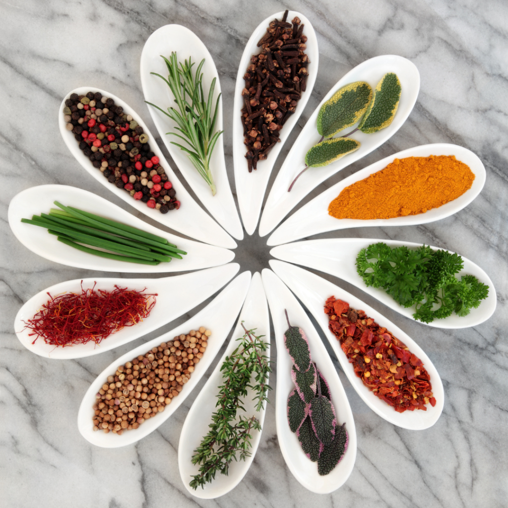 Various spices in white dishes that form a flower when placed together, spices include rosemary, chili flakes, parsley, and thyme for more flavor.