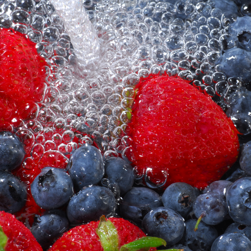 Strawberries and blueberries being washed as part of a simple "fruit and veggie bath" food play fun activity.