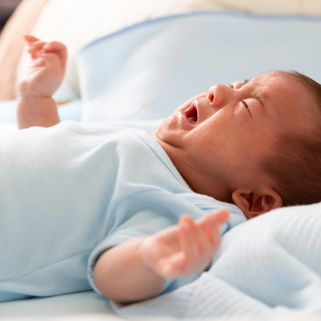 Baby constipation can be very painful, as shown here with an infant crying while lying down.